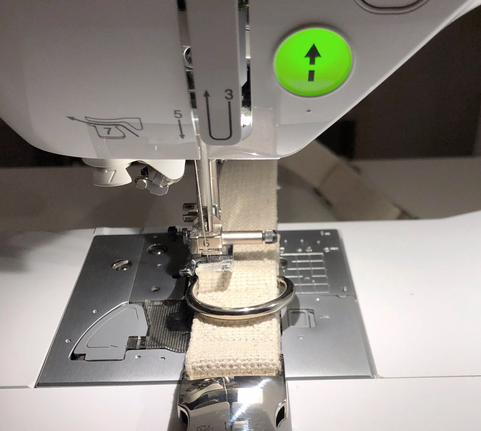 sewing machine close up with silver buckle and ring. Needle going into thick hemp webbing