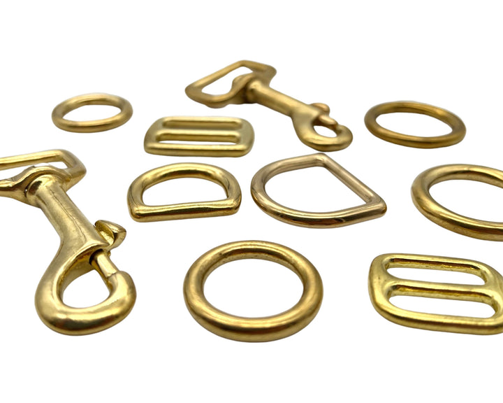 solid brass golden snap clips, d rings, orings and tri glides on white background