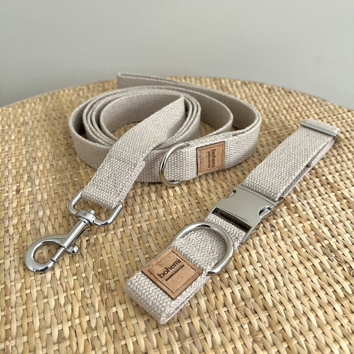 hemp webbing dog collar and lead on a rattan table. Silver buckles, rings and clips and a natural brown square logo reading bohemi